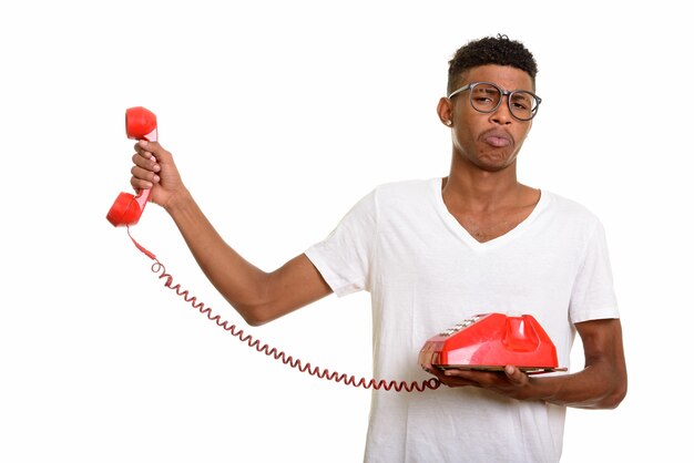 Young handsome man looking annoyed while holding telepho