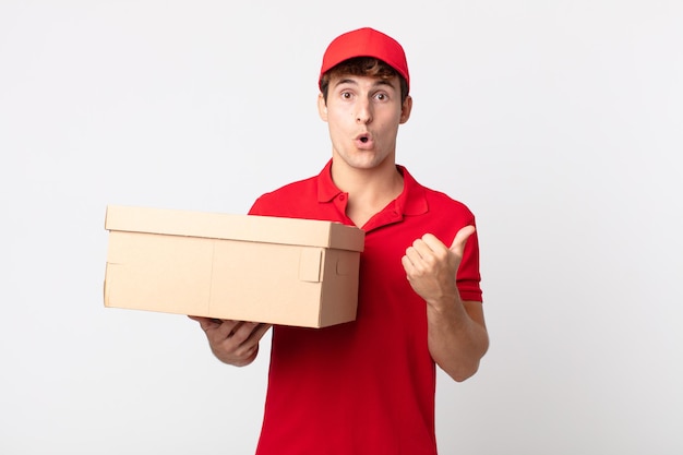 Young handsome man looking astonished in disbelief delivery package service concept