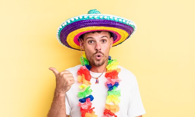 Young handsome man looking astonished in disbelief. mexican party concept