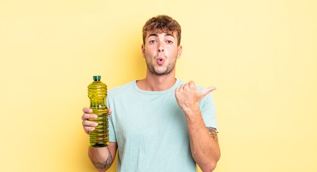 Young handsome man looking astonished in disbelief. olive oil concept