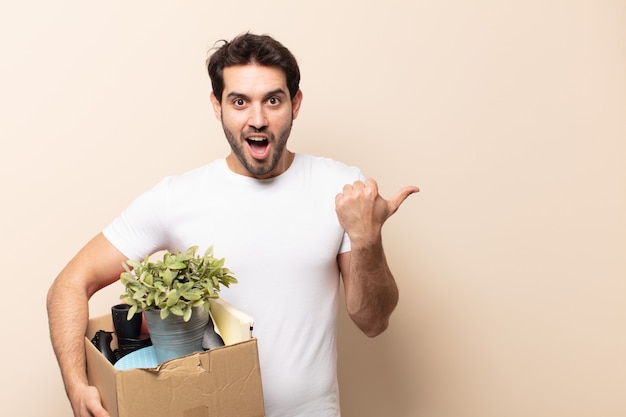 Young handsome man looking astonished in disbelief, pointing at object on the side and saying wow, unbelievable