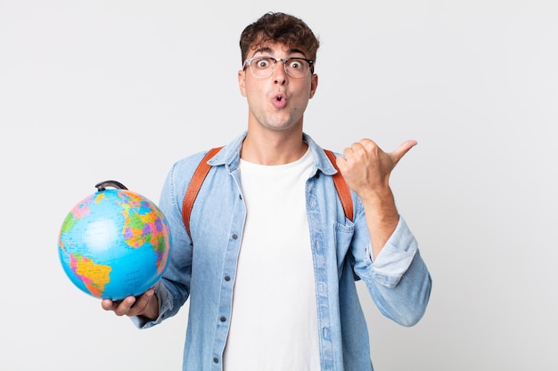 Young handsome man looking astonished in disbelief. student holding a world globe map