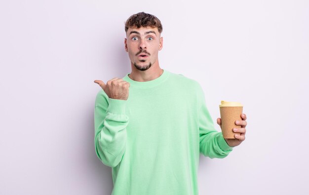 Young handsome man looking astonished in disbelief. take away coffee concept