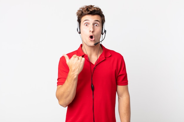 Young handsome man looking astonished in disbelief. telemarketer concept