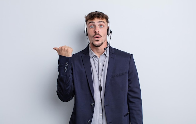 Young handsome man looking astonished in disbelief. telemarketer concept