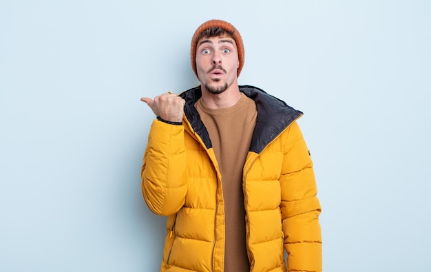 Young handsome man looking astonished in disbelief. winter concept