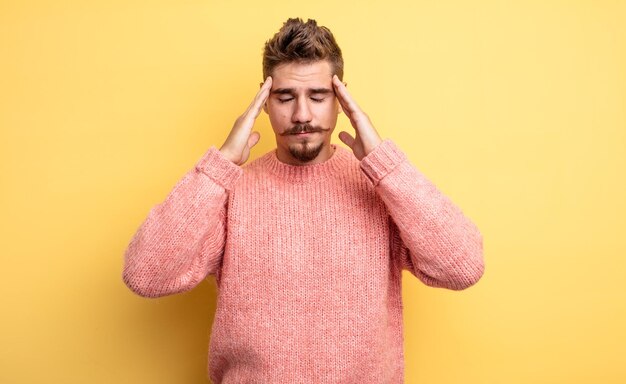 Young handsome man looking concentrated, thoughtful and inspired, brainstorming and imagining with hands on forehead. strange moustache concept