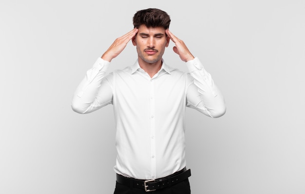 young handsome man looking concentrated, thoughtful and inspired, brainstorming and imagining with hands on forehead