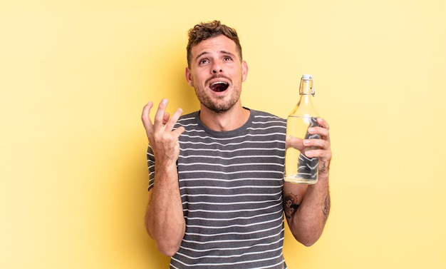 Young handsome man looking desperate, frustrated and stressed. water concept