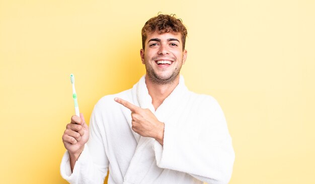 Young handsome man looking excited and surprised pointing to the side. toothbrush concept