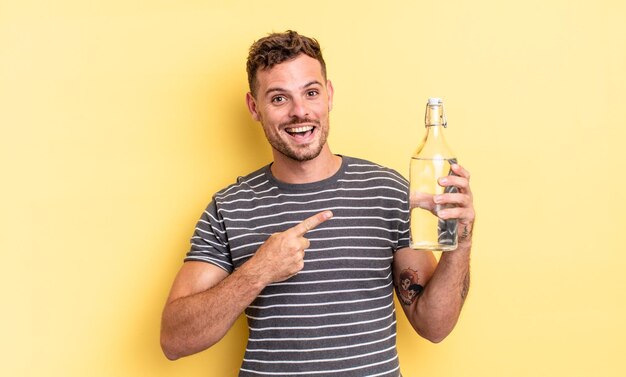 Young handsome man looking excited and surprised pointing to the side. water concept