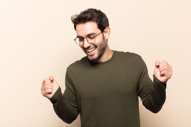 Young handsome man looking extremely happy and surprised, celebrating success, shouting and jumping