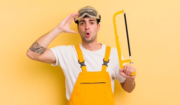 Young handsome man looking happy astonished and surprised handyman concept