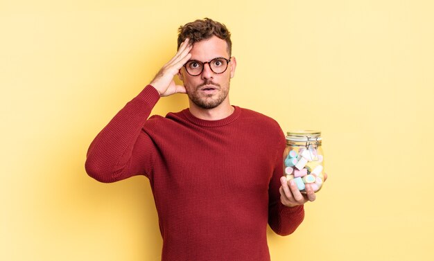 Young handsome man looking happy, astonished and surprised. jelly candies concept