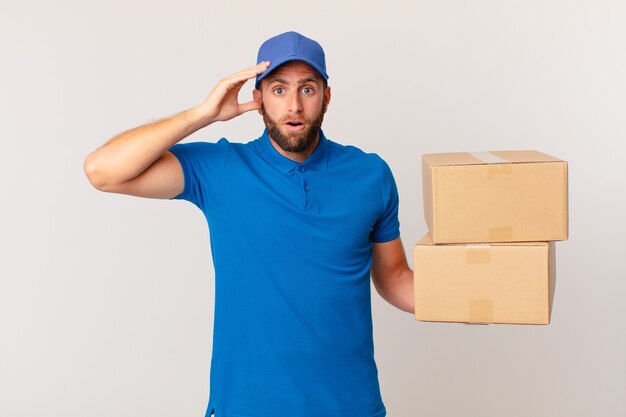 young handsome man looking happy, astonished and surprised. package delivering concept