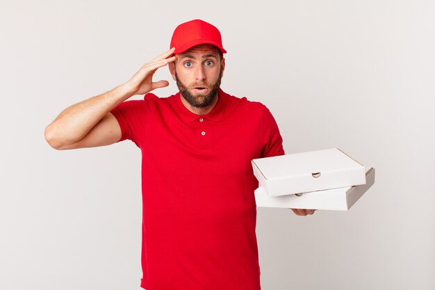Young handsome man looking happy, astonished and surprised. pizza delivering concept