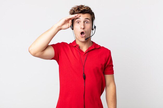 Young handsome man looking happy, astonished and surprised. telemarketer concept