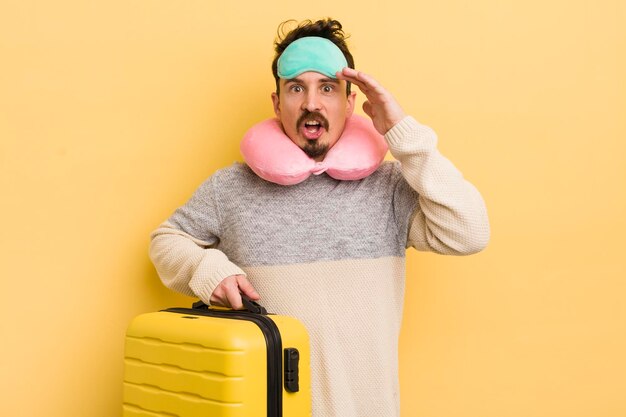 Young handsome man looking happy astonished and surprised travel passenger concept