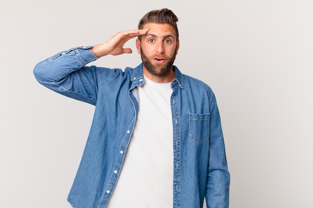 Young handsome man looking happy, astonished and surprised