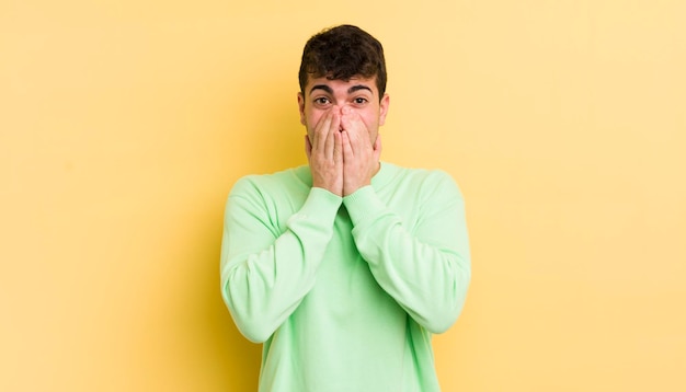 Young handsome man looking happy cheerful lucky and surprised covering mouth with both hands