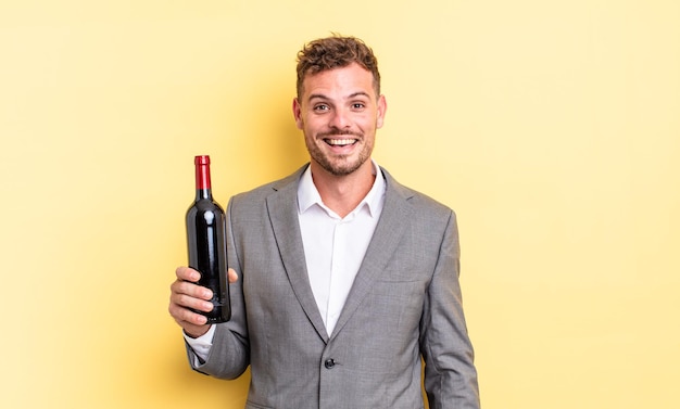 Young handsome man looking happy and pleasantly surprised. bottle of wine concept