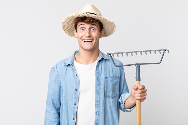 Young handsome man looking happy and pleasantly surprised. farmer concept