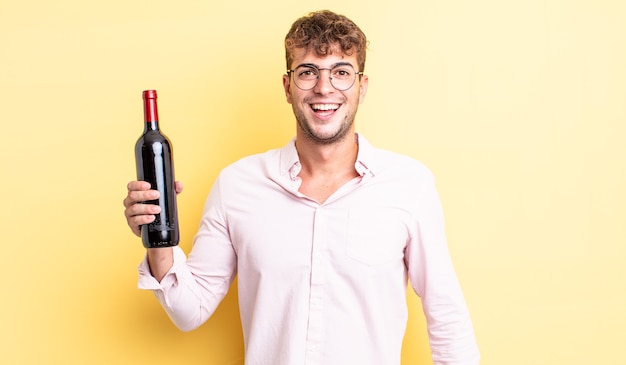 Young handsome man looking happy and pleasantly surprised. wine bottle concept