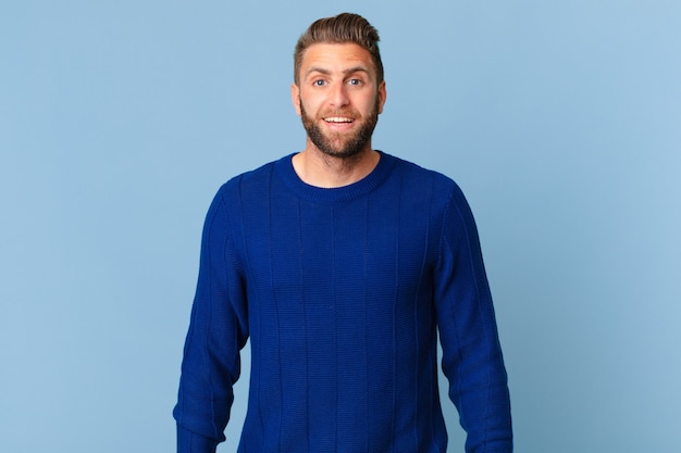 young handsome man looking happy and pleasantly surprised