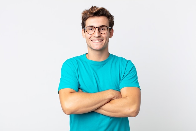 young handsome man looking like a happy, proud and satisfied achiever smiling with arms crossed