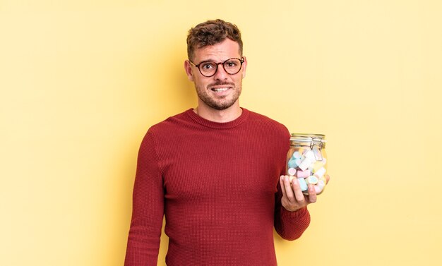 Young handsome man looking puzzled and confused. jelly candies concept