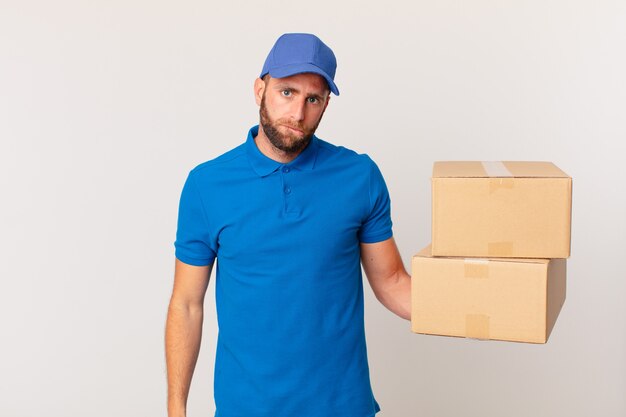 Young handsome man looking puzzled and confused. package delivering concept