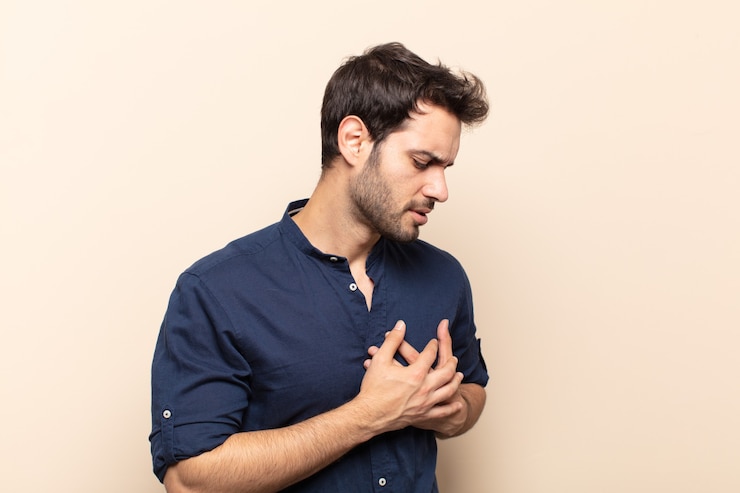 Photo young handsome man looking sad, hurt and heartbroken, holding both hands close to heart, crying and feeling depressed