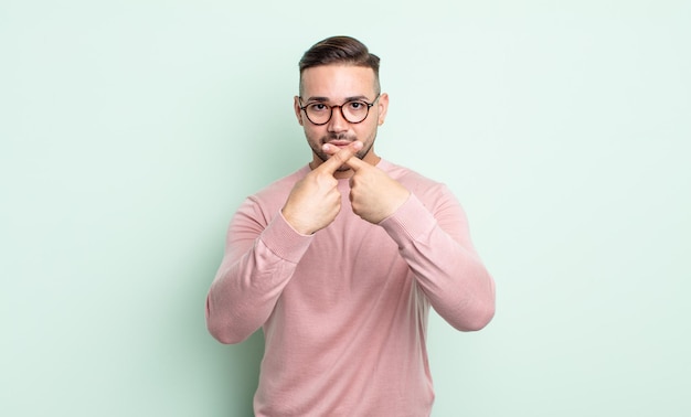 Young handsome man looking serious and displeased with both fingers crossed up front in rejection, asking for silence