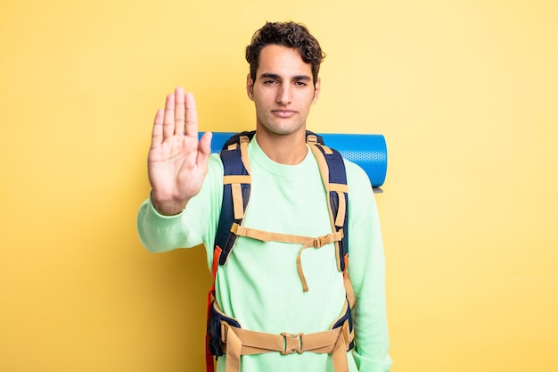 Young handsome man looking serious showing open palm making stop gesture