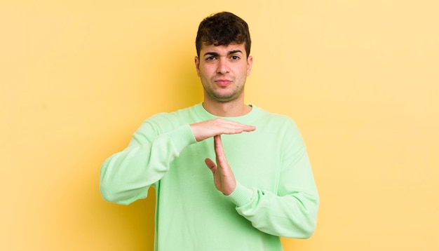 Young handsome man looking serious stern angry and displeased making time out sign