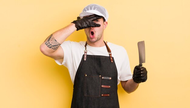 Young handsome man looking shocked scared or terrified covering face with hand butcher concept