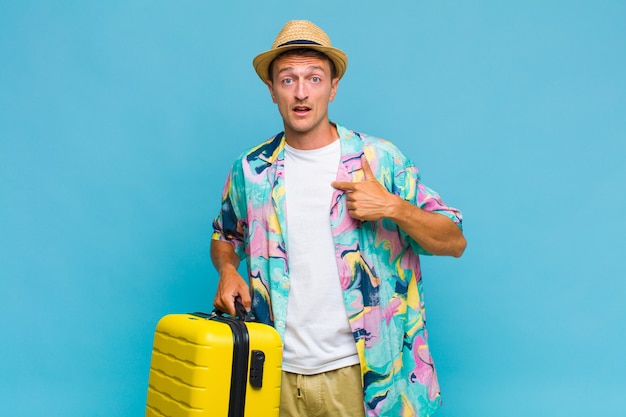 Young handsome man looking shocked and surprised with mouth wide open, pointing to self