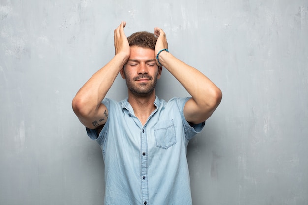 Young handsome man looking stressed and frustrated, expressing dismay and disbelief.