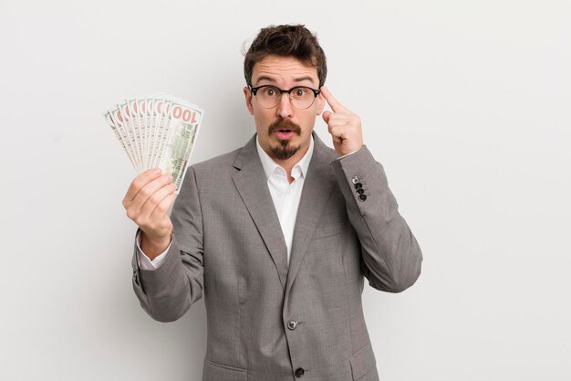 Young handsome man looking surprised realizing a new thought idea or concept businessman and banknotes