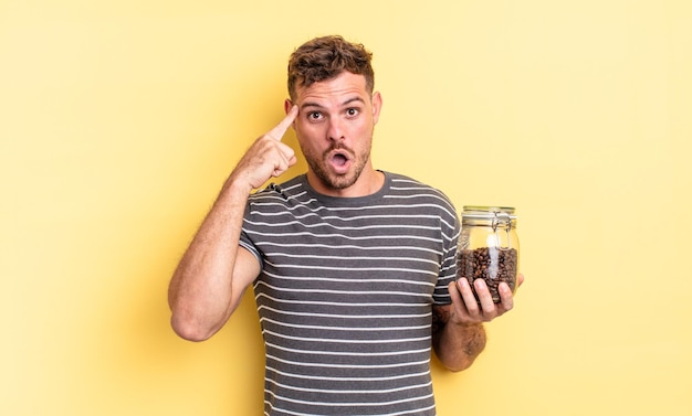 Young handsome man looking surprised, realizing a new thought, idea or concept coffee beans concept