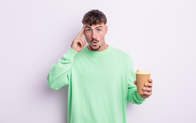 Young handsome man looking surprised, realizing a new thought, idea or concept. take away coffee concept