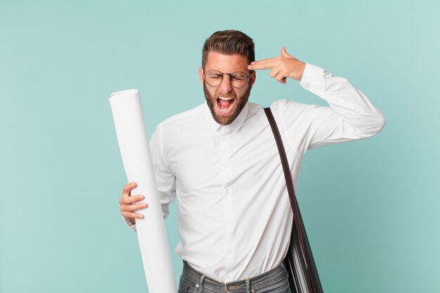 Young handsome man looking unhappy and stressed, suicide gesture making gun sign. architect concept