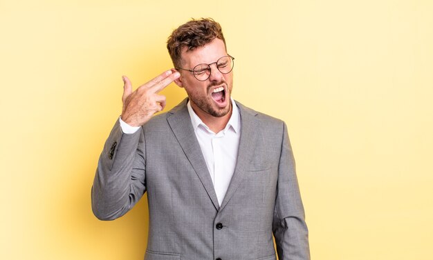 young handsome man looking unhappy and stressed, suicide gesture making gun sign. business concept