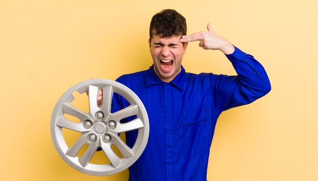 Young handsome man looking unhappy and stressed suicide gesture making gun sign car repairman concept