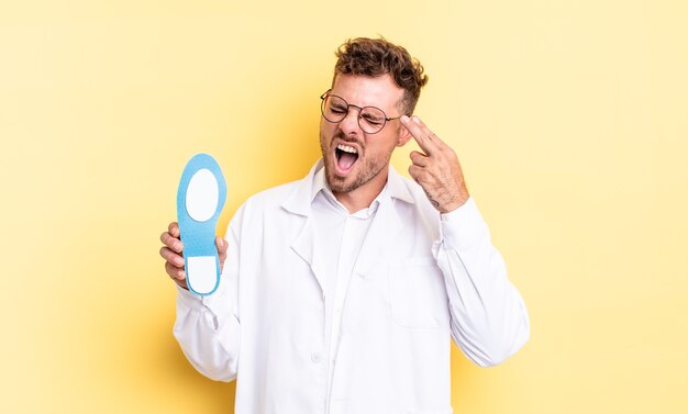 Young handsome man looking unhappy and stressed, suicide gesture making gun sign. chiropodist concept