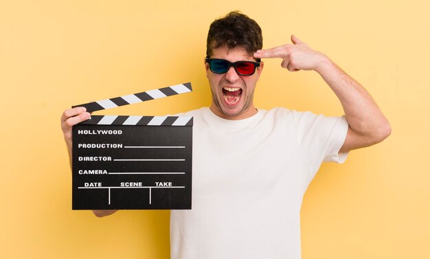 Foto giovane bell'uomo che sembra gesto suicida infelice e stressato facendo segno di pistola concetto di clapper cinematografico