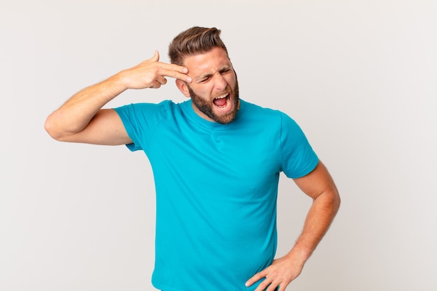 Young handsome man looking unhappy and stressed, suicide gesture making gun sign. fitness