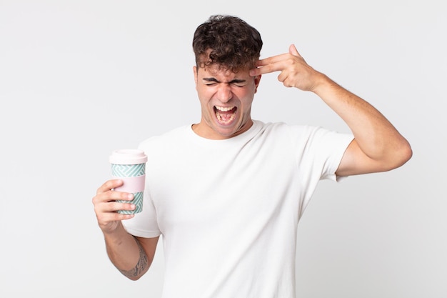 Young handsome man looking unhappy and stressed, suicide gesture making gun sign and holding a take away coffee