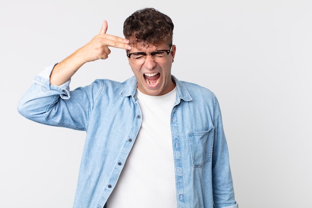 Young handsome man looking unhappy and stressed, suicide gesture making gun sign with hand, pointing to head