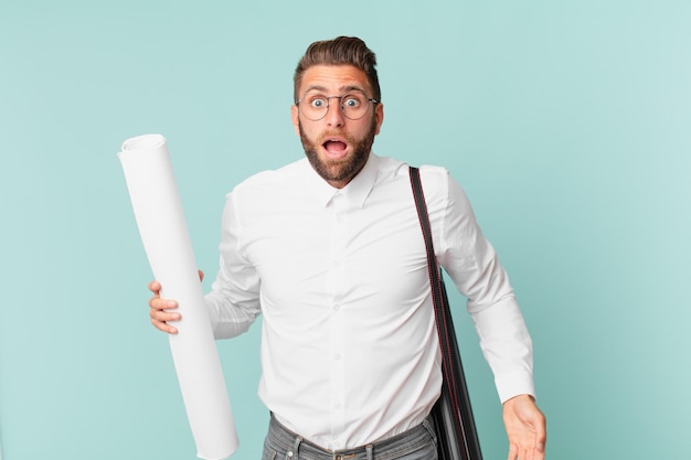 Young handsome man looking very shocked or surprised. architect concept